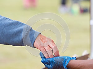 A customer hand places money in a blue hygiene gloved hand worn to avoid transmission and cross infection