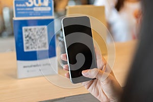 Customer hand using digital mobile phone scan QR code pay for buying coffee in modern cafe coffee shop, cafe restaurant, digital p