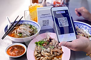 Customer hand using smart phone to scan QR code tag with blur noodles or chinese food and blurry soft drik to accepted generate