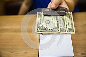 Customer handed the cash on bill paper. US dollar banknote tips in leather black bill reciept.