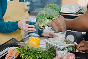 Customer handing a sales assistant broccoli