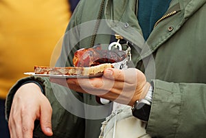 Customer holding bread with sausage at farmers market.