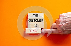 Customer is king symbol. Wooden blocks with words `The customer is king`. Male hand. Beautiful orange background. Business and