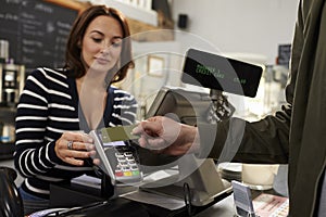 Customer making a contactless card payment over shop counter