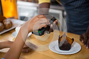 Customer paying barista through smart phone in coffee shop