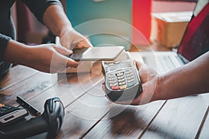 Customer paying bill through smartphone using NFC technology.Closeup of hand making payment through contactless machine