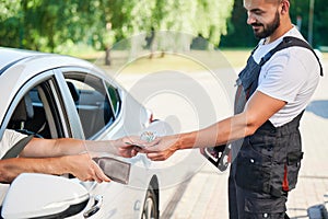 Customer paying by cash to smiling gas station operator