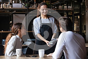 Customer paying by contactless credit card, attractive waitress holding reader