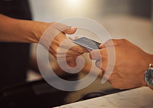 Customer paying with a credit card in a cafe. Closeup of a customer paying a barista in a restaurant. Hands of a shop