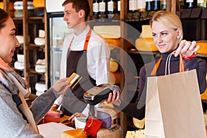 Customer paying for order of cheese in grocery shop.