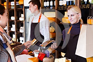 Customer paying for order of cheese in grocery shop.