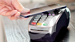 Customer paying with NFC technology by mobile phone on terminal.
