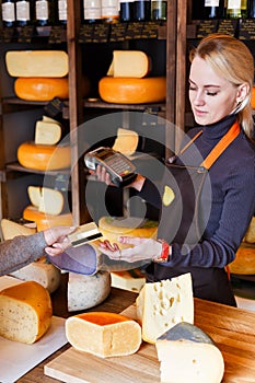 Customer paying for order of cheese in grocery shop.