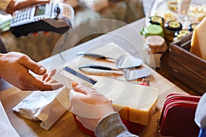 Customer paying for order of cheese in grocery shop.