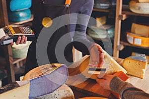 Customer paying for order of cheese in grocery shop.