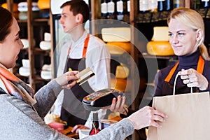 Customer paying for order of cheese in grocery shop.