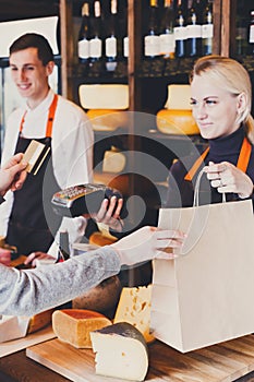 Customer paying for order of cheese in grocery shop.