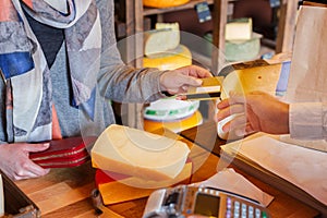 Customer paying for order of cheese in grocery shop.