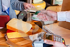 Customer paying for order of cheese in grocery shop.