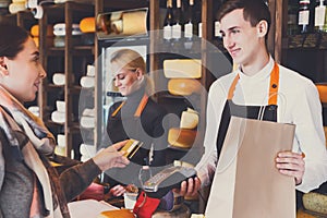 Customer paying for order of cheese in grocery shop.