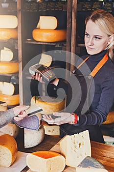 Customer paying for order of cheese in grocery shop.