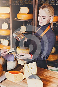 Customer paying for order of cheese in grocery shop.