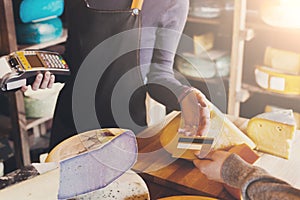 Customer paying for order of cheese in grocery shop.