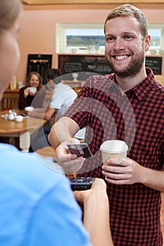 Customer Paying For Takeaway Coffee Using Contactless Terminal