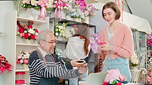 Customer payment by scanning phone application to elderly male florist owner.
