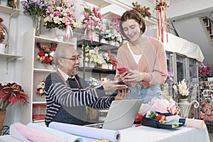 Customer payment by scanning phone application to elderly male florist owner.
