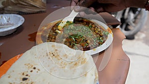 A customer with a plate of Kulche Chole with butter and sliced Dhania