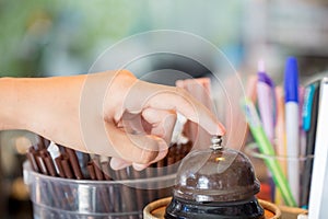 Customer`s hand pressing bell on counter at coffee shop