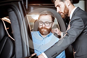 Customer with a sales manager inspecting modern car in the showroom