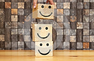 customer satisfaction concept, hand putting 3d big wooden cube with happy face