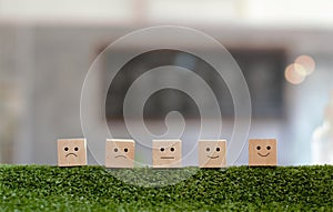 Customer satisfaction concept. Wood blocks rating with smile face on green grass.