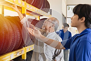 Customer selecting car tyres in garage and sale staff recommend various types of vehicle tires