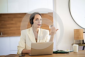 Confident woman with headshet and laptop working at home