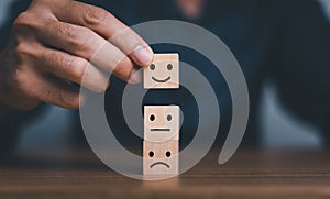 Customer service evaluation and satisfaction survey concepts. Close-up hand picked the happy face smile face symbol on wooden