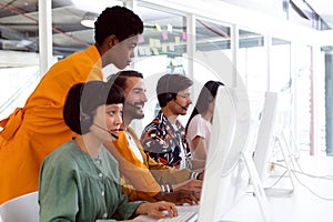 Customer service executive trainer assisting her team at desk