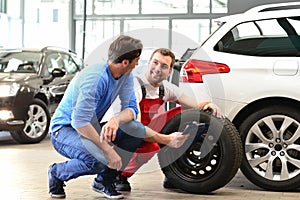 customer service in the garage - mechanic discusses repair and tyre change with one man