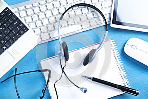 Customer service headset, computer keyboard and business objects on the blue background