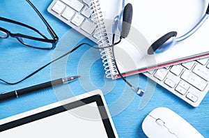 Customer service headset, computer keyboard and business objects on the blue background