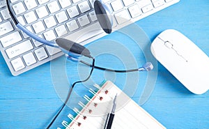 Customer service headset, computer keyboard and business objects on the blue background