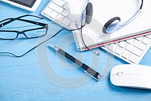 Customer service headset, computer keyboard and business objects on the blue background