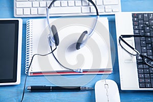 Customer service headset, computer keyboard and business objects on the blue background