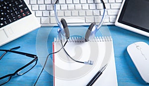 Customer service headset, computer keyboard and business objects on the blue background