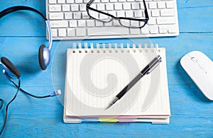 Customer service headset, computer keyboard and business objects on the blue background