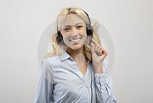 Customer service operator. Portrait of happy female call center representative in headset, posing over grey background