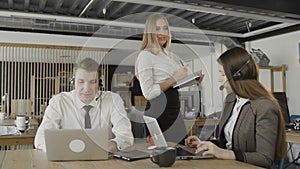 Customer service operators taking calls in busy call center, manager check their work