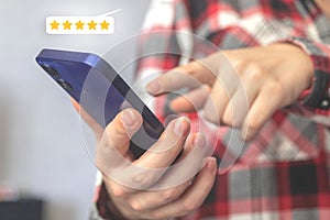 Customer service rating concept background, woman hand hold smartphone and press on the screen with five gold star, best